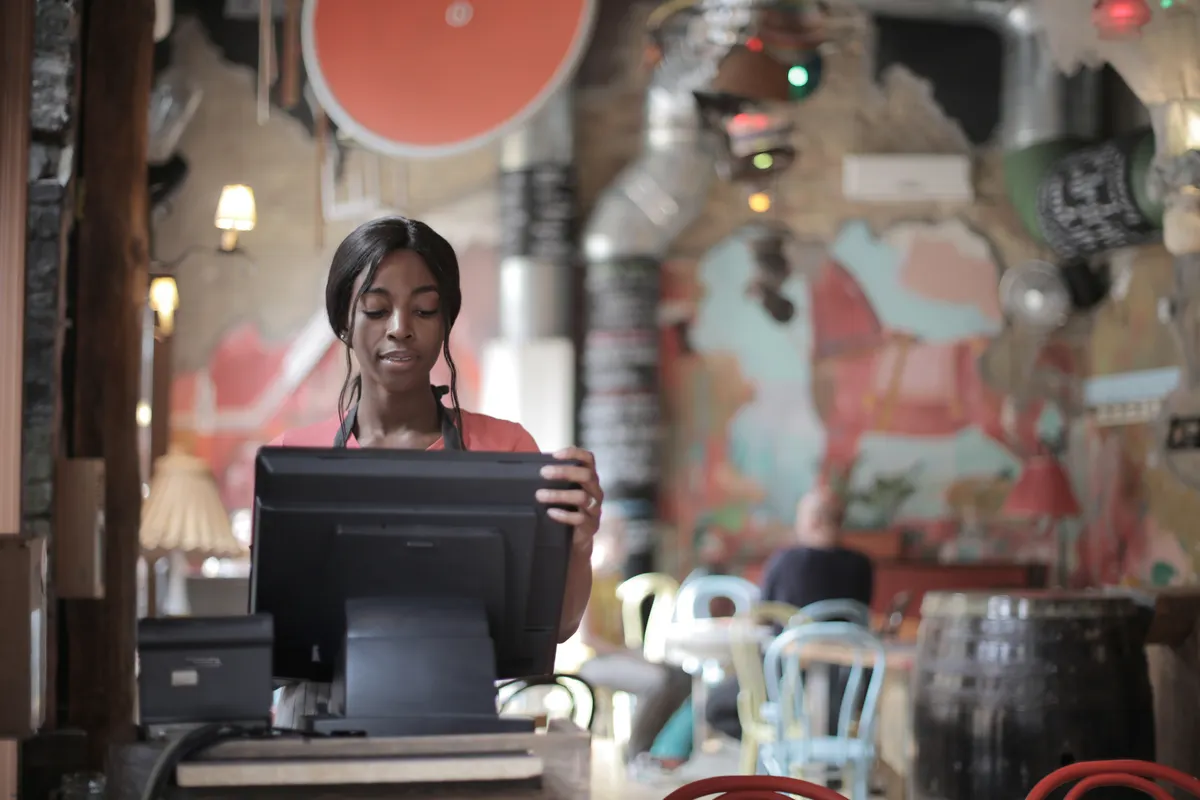 Employée souriante à la caisse d’un restaurant animé