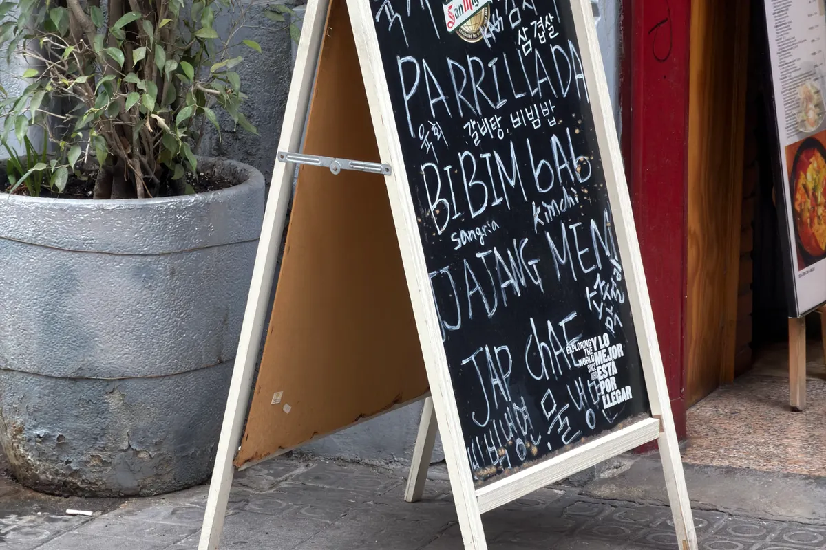Ardoise de menu posée sur le trottoir devant un restaurant